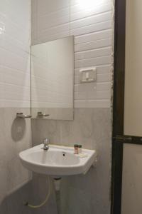ein Badezimmer mit einem weißen Waschbecken und einem Spiegel in der Unterkunft Hotel Om Palace in Lonavla