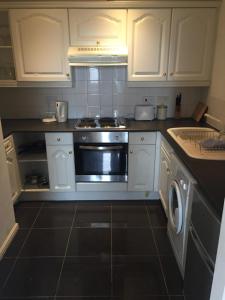a kitchen with white cabinets and a stove at Fabulous Dockside Apartment in Liverpool