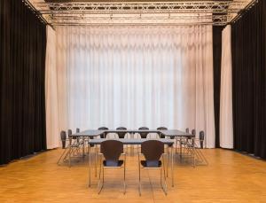 eine Gruppe von Tischen und Stühlen in einem Zimmer mit Vorhängen in der Unterkunft Seminarhaus S1516 in Berlin