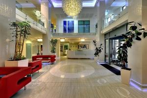 a lobby with red chairs and plants in a building at St. Joseph Royal Regent in Karlovy Vary +39 photos