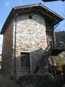 a small stone building with a wooden door and stairs at Stalut das puestines in Arta Terme