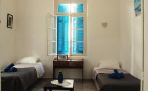 a room with two beds and a window with blue shutters at Marika's Traditional House in Agios Nikolaos