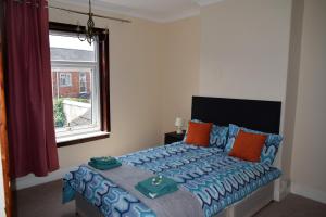 Schlafzimmer mit einem Bett mit blauen und orangefarbenen Kissen in der Unterkunft Kavig House in Lincoln