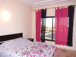 Schlafzimmer mit einem Bett und einem Fenster mit rosa Vorhängen in der Unterkunft Luxueux Appart Au Centre Ville in Fès