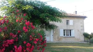 une maison avec des fleurs roses devant elle dans l'établissement 12 Grand Sable, à Saint-Émilion