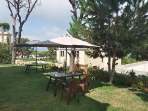 una mesa y sillas bajo una sombrilla en la hierba en Honey Guesthouse, en Jezzîne