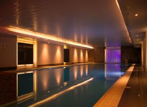 a swimming pool in a building at night at The Continental Hotel and Spa, Heathrow in Hounslow