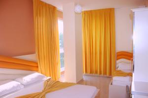 a bedroom with two beds and a window with yellow curtains at Hotel Garden in Vlorë