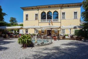 a building with a fountain and umbrellas in front of it at Villa Quaranta Tommasi Wine Hotel & SPA in Pescantina