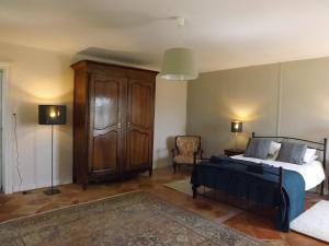 a bedroom with a bed and a cabinet and a chair at La Petite Auberge in Comps