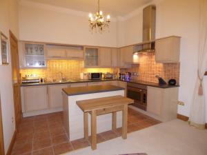 a kitchen with white cabinets and a wooden table at The Pipers No 7 Lomond Castle in Balloch