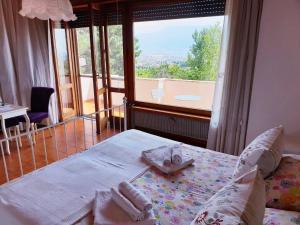 a bedroom with a bed with towels and a large window at B&B Il Giardino di Villa Anna in Trecase