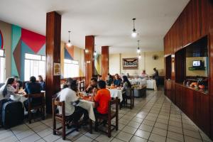 a group of people sitting at tables in a restaurant at Hotel JB in Bom Despacho
