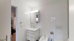 a white bathroom with a sink and a mirror at Arsa 26 in Silvaplana +13 photos
