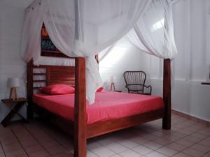 a bedroom with a bed with red sheets and a canopy at Villa BonBon Siwo in Le Diamant +36 photos