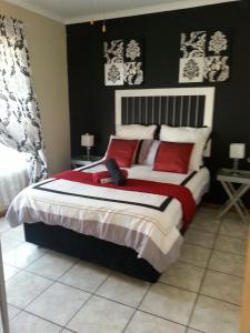 a bedroom with a large bed with red pillows at Queens Villa Guest House in Zeerust