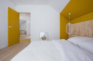 a bedroom with a white bed and a yellow wall at Colors Apartments Zator - tylko 10 minut piechotą od Energylandii in Zator