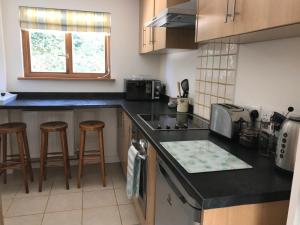 a kitchen with black counter tops and wooden stools at Windrush Apartment in Witney