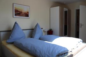 1 dormitorio con 1 cama con almohadas azules en Alpaca-Village, en Lauterbach