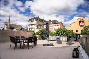 a patio with chairs and a table and an umbrella at Résidence le XV in Bagnères-de-Bigorre