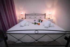 a white bed with two pillows and flowers on it at Aias Summer House in Aiándion