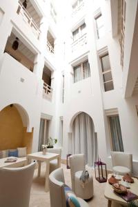 a large white building with tables and chairs at Riad Dar Maya in Essaouira