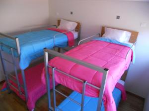 Azores Youth Hostels - São Jorge في Calheta: سريرين بطابقين في غرفة وردية وأزرق