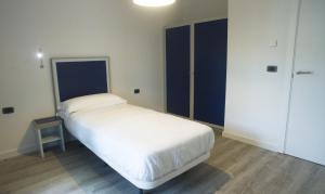 a small bedroom with a white bed and blue doors at Piamarta Apartments in Toscolano Maderno +15 photos