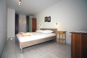 a bedroom with a large bed and a wooden table at Apartmani TEO in Tisno