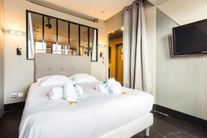 a white bed with white pillows and a flat screen tv at CMG - Tour Eiffel - 75 in Paris