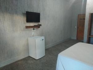 a room with a small refrigerator and a tv on the wall at Orla Piaui in Luis Correia