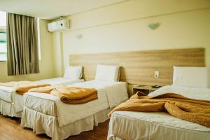 a hotel room with two beds with blankets on them at Dalle Hotel in Bagé