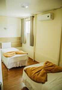 a hotel room with two beds with brown blankets at Dalle Hotel in Bagé