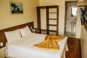 a bedroom with a white bed with a blanket on it at Dalle Hotel in Bagé