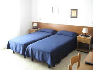 duas camas num quarto de hotel com lençóis azuis em B&B Garnì Da Vito em Lido di Jesolo