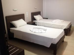 two beds in a hotel room with white sheets at Hotel Thisvi in Stalís