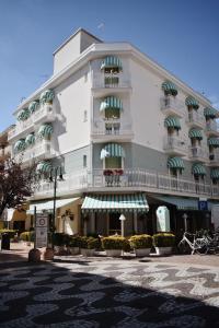 a large white building with balconies on a street at Hotel Flora in Cattolica