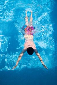 une personne nageant dans l'eau d'une piscine dans l'établissement Hotel Meira, à Vila Praia de Âncora