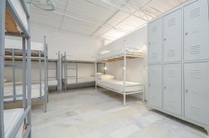 a room with three bunk beds and a hallway with cabinets at Hostel Naxos Camping in Naxos Chora