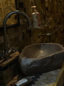 um lavatório de pedra numa casa de banho com uma torneira em Fullhouse em Mataram