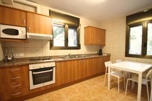 uma cozinha com armários de madeira, uma mesa branca, uma mesa e um micro-ondas em Pont de Toneta 6,3 Atico Duplex, Ransol, Zona Grandvalira em Ransol