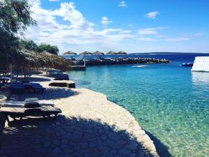 a beach with chairs and umbrellas in the water at Holiday Park Mandrice in Mandre
