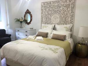 a bedroom with a large white bed with a mirror at Lisboa 1912 - Alojamento de Charme in Lisbon