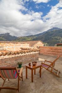 a patio with two chairs and a table and a brick wall at Hostal El Caminante in El Cocuy