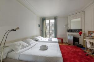 Habitación blanca con 2 camas y alfombra roja. en Veeve - Balcony Bliss, en París