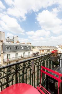 un banco rojo en un balcón con vistas a los edificios en Veeve - Balcony Bliss, en París