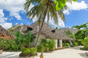 a resort with thatched roofs and a palm tree at Maji Lodge in Matemwe