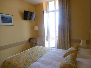 a bedroom with a bed and a large window at Hôtel La Flore in Villefranche-sur-Mer