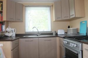 a kitchen with a sink and a stove and a window at The Valley Static Caravan in Pembrokeshire