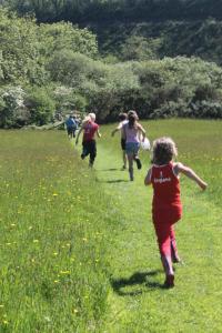 a group of children running in a field with a frisbee at The Valley Static Caravan in Pembrokeshire